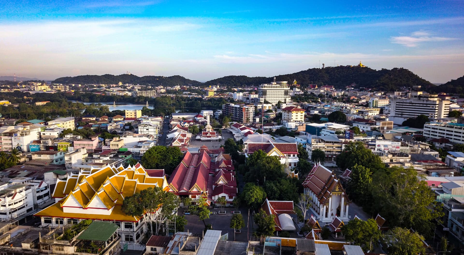 Aerial view of a Thai city with temples and neighborhoods stretching to the hills