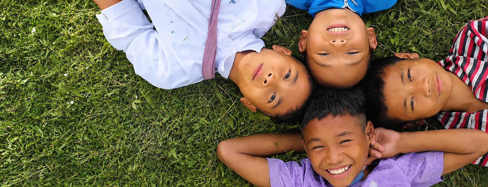 Children smiling together while lying on green grass in Asia
