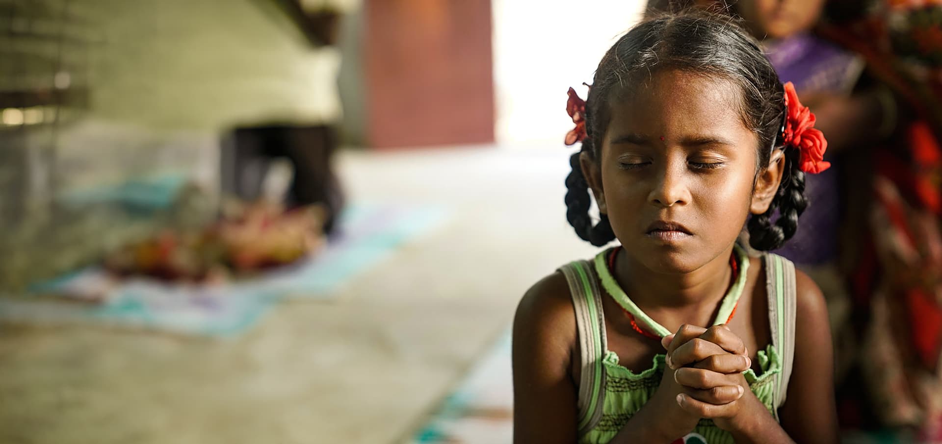 Young girl with folded hands praying at a mission school