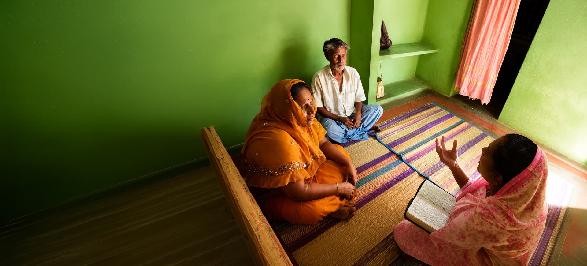 A Bible worker giving a Bible study to a family in their home